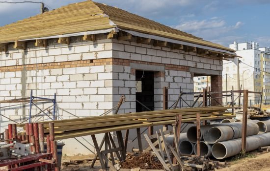 Building site of a house under construction. Unfinished house walls made from white aerated autoclaved concrete blocks. Wooden truss system. construction company in london